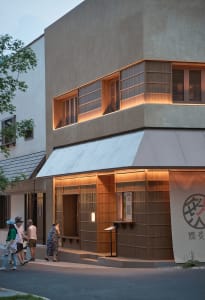 A modern Asian building with a large window, surrounded by pedestrians and lively atmosphere