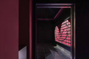 Industrial hallway with a red accent wall, black and white checkered flooring, and concrete walls