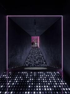 A dark and sleek hallway with a black background, illuminated pathway, and contemporary design elements
