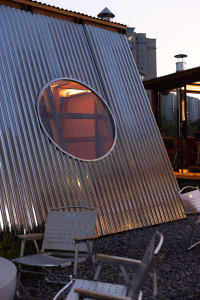 A modern dome-shaped building with a metal exterior, featuring a seating area with chairs and a couch, conveying a sense of innovation and creativity in design