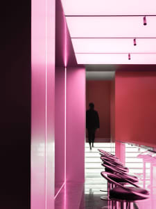 Dimly lit space with pink walls, red accents, modern chairs, and a bold, contemporary style