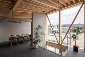 Warm and inviting living area with wood flooring and walls, featuring a dining table, chairs, and a potted plant