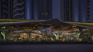 A modern building with traditional elements, featuring a large glass structure and potted plants, set against a nighttime backdrop