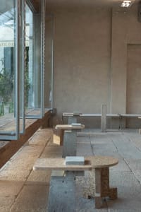 Empty industrial dining space with a concrete floor, stone bench, and cement blocks, featuring a minimalist and functional atmosphere
