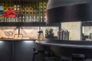 A modern Asian restaurant with a black theme, featuring a counter with stools and decorative walls