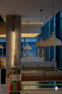 A modern restaurant interior with wood accents, multiple dining tables, and well-placed lamps creating a cozy atmosphere
