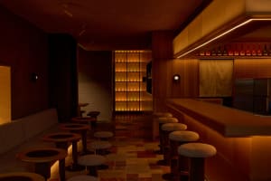 A warm and inviting bar area with a wooden countertop, stools, and bottles on display behind the bar