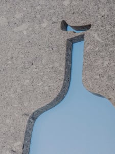 A modern space with a glass bottle on a stone wall, suggesting industrial or minimalist design elements