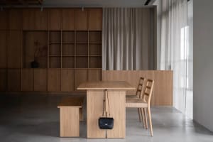 A wooden dining table and chairs in a clean and organized room with a sense of calmness and sophistication