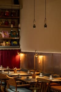 A cozy dining area in a restaurant with a long wooden table and chairs, cups and bowls on the table, and an inviting atmosphere