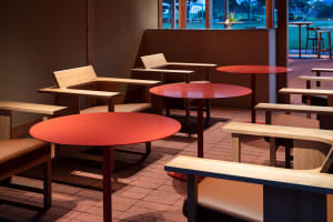A warm and inviting dining area with multiple wooden tables and chairs in various arrangements, perfect for social gatherings or meals