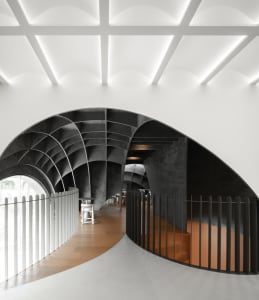 Open modern space with a curved wall, chairs, and a minimalist atmosphere