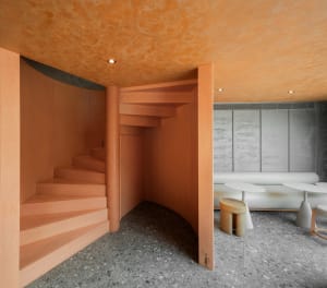A modern living space with a spiral wooden staircase, orange walls, and a cozy bench at the base of the stairs