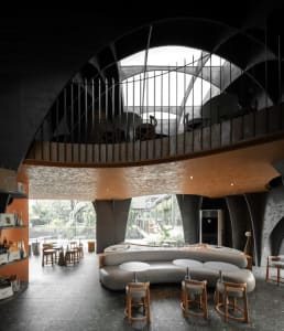 Modern restaurant interior with a circular dining area, wooden tables, and chairs, featuring a bar and multiple dining tables