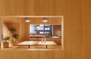 Cozy restaurant interior with wooden walls, tables, and chairs, surrounded by potted plants