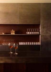 A bar area with a wooden countertop, wine glasses, and bottles, creating a cozy and inviting atmosphere