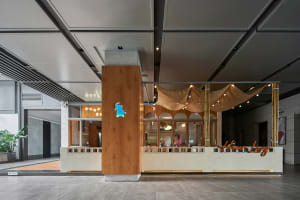 Warm and inviting restaurant interior with a wooden bar and multiple dining tables, featuring a cozy atmosphere and wooden elements