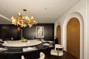 A round dining table set for dinner in a modern restaurant with wine glasses and cups, surrounded by chairs in a sophisticated atmosphere
