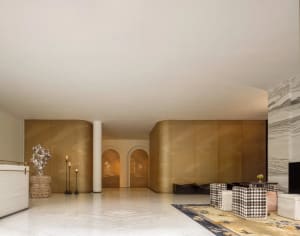 Spacious hotel lobby with a checkered rug, gold accents, two couches, chairs, a dining table, and decorative vases
