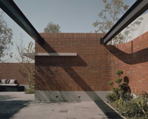A brick building with a large archway, surrounded by trees, with a warm and traditional appearance