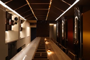 A modern restaurant dining area with wooden tables, chairs, and candles, creating a warm and inviting atmosphere for guests