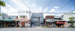 A bustling city street scene with two buildings, pedestrians, and outdoor seating area