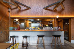 Warm and inviting kitchen with wooden walls and floors, featuring a dining table and chairs, and a countertop with various items