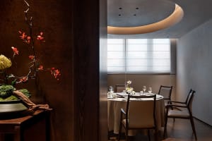 A formal dining area with a round table set with various items, surrounded by chairs with and without backs, creating a sophisticated atmosphere