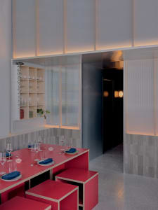 Elegant dining space with multiple tables, chairs, wine glasses, and modern tile flooring