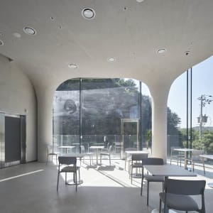 A modern restaurant interior with multiple dining tables and chairs, well-lit for a comfortable atmosphere