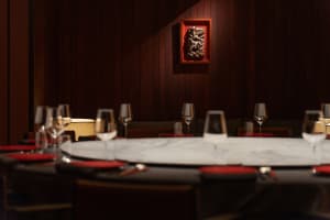Formal dining space with a round table, wine glasses, and multiple chairs in a sophisticated environment