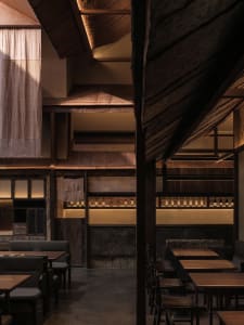Empty restaurant interior with wooden floors and walls, featuring chairs placed throughout the space to create a calm and inviting atmosphere
