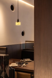 Cozy dining area with a wooden table, chairs, cups, a bowl, and a spoon, surrounded by warm and inviting decor