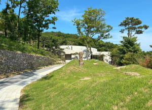 A stone house surrounded by trees in a grassy area, creating a serene atmosphere