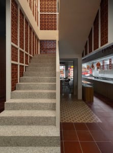A well-lit restaurant interior with a stone staircase, chairs, and dining tables, creating a welcoming atmosphere for patrons