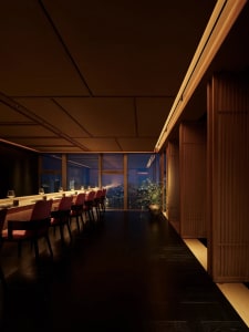 A cozy restaurant dining area with a long wooden table surrounded by leather-upholstered chairs, creating a warm and inviting atmosphere