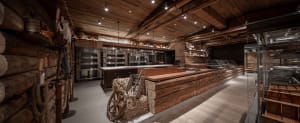 Industrial kitchen with wooden walls and floors, multiple ovens, and bottles, with a rustic and functional atmosphere