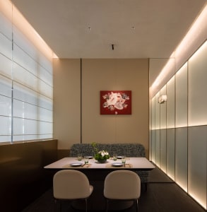 Elegant dining space with a wooden table and chairs, a vase on the table, and a warm atmosphere