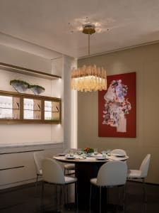 A dining area with a large wooden table and chairs, illuminated by a chandelier, with wine glasses on the table, creating an elegant and sophisticated atmosphere