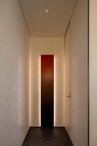 A well-lit hallway with a white wall, two doors, and a red light strip, creating a bright atmosphere