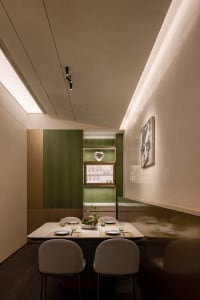 Sophisticated dining area with a large wooden table, chairs, wine glasses, and cups, set for a special occasion or dinner event
