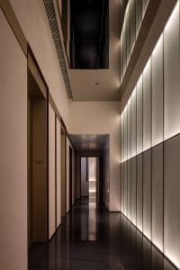 A clean and modern office hallway with white walls and floors, featuring three doors with different materials and ample lighting