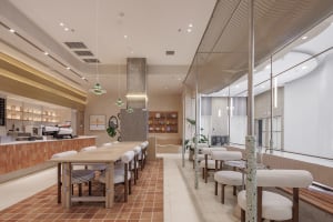 Open restaurant interior with multiple tables, chairs, and potted plants, creating a welcoming atmosphere