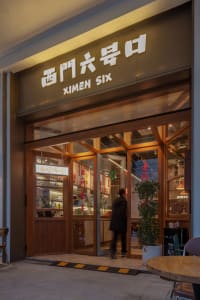An inviting Asian restaurant with wooden walls, a large sign, and chairs and bottles on display