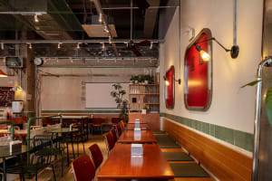 Warm and inviting Asian restaurant interior with wooden tables, red accents, and potted plants
