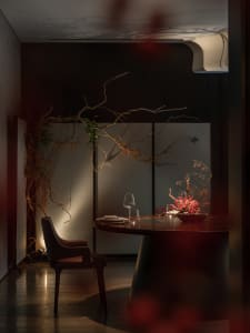 Intimate dining space with a darkly lit room, a dining table, and two chairs, with a wine glass on the table
