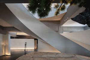 Modern building with multiple levels, concrete exterior, and a spiral staircase, featuring two people in a minimalist setting