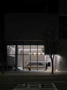 A modern dining space with a concrete floor and walls, a dining table, chairs, and warm lighting