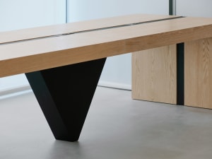 A modern dining space with a large wooden table on a concrete floor, giving an industrial feel