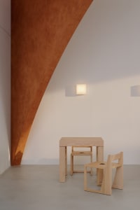 A cozy dining space with a wooden table and chairs in a minimalist white room